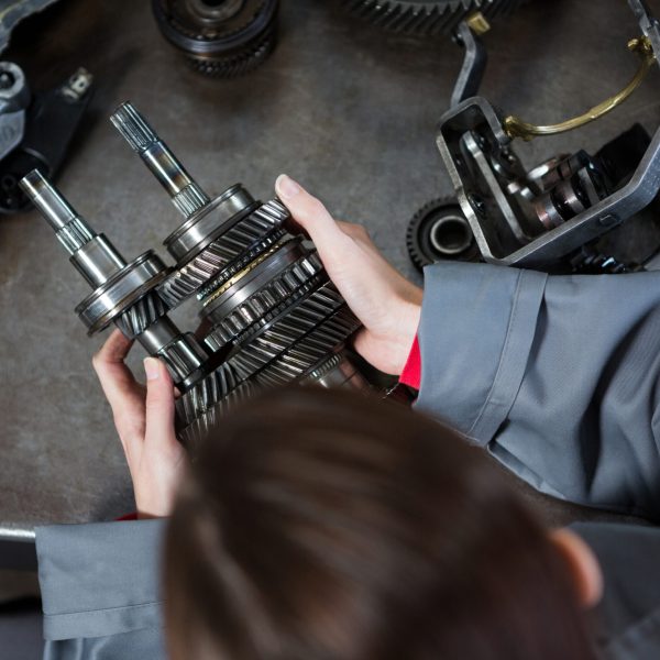 Female mechanic holding spare parts at repair garage
